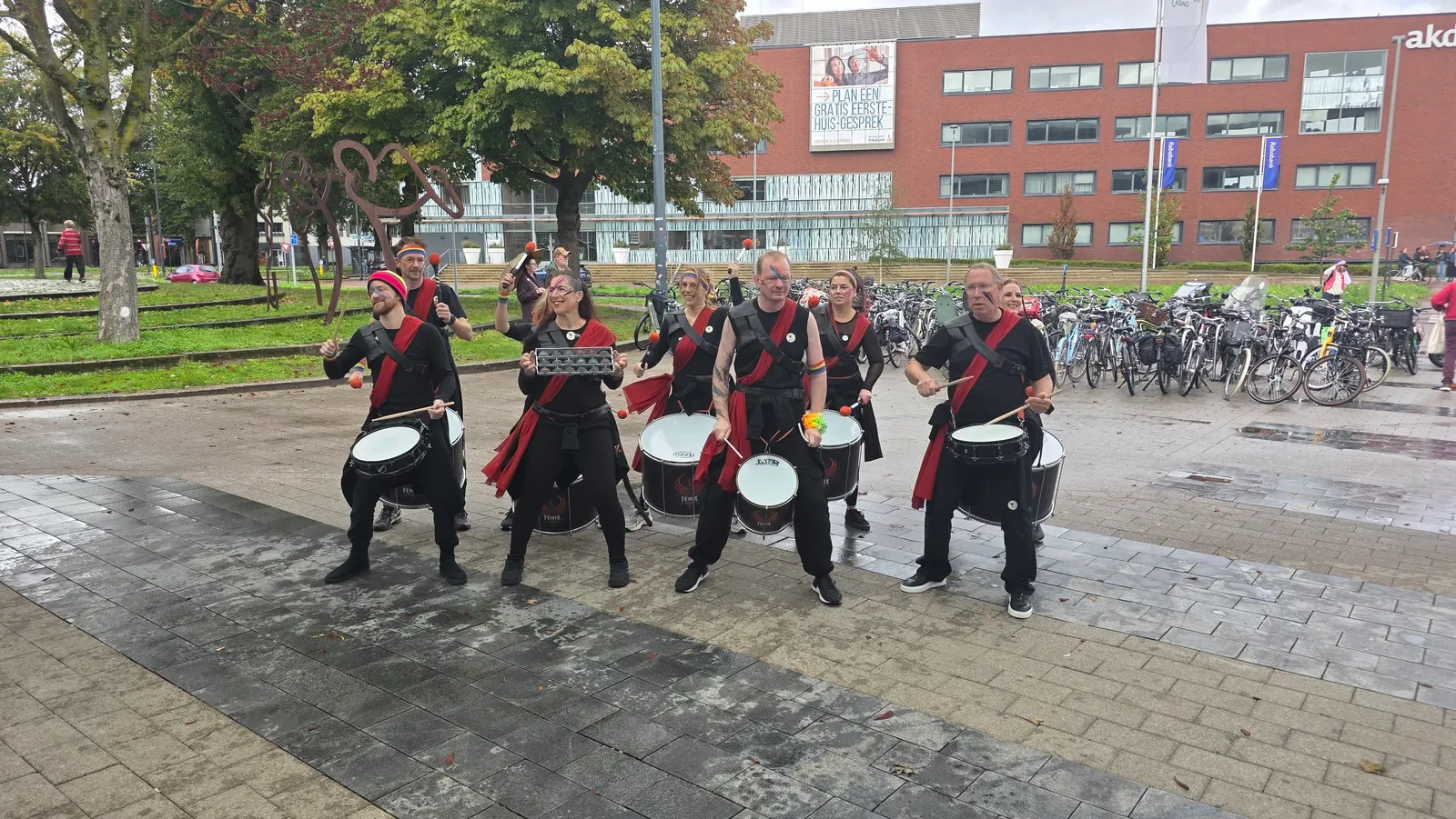 Fenix Drums speelt met snaredrums op een plein, met fietsen en een kantoorgebouw op de achtergrond